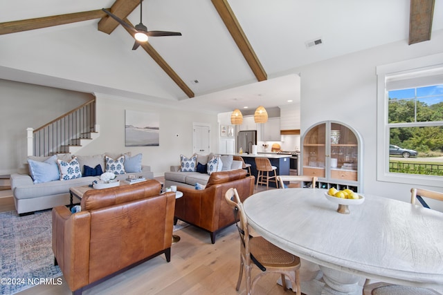 dining space featuring beamed ceiling, ceiling fan, light wood-type flooring, and high vaulted ceiling