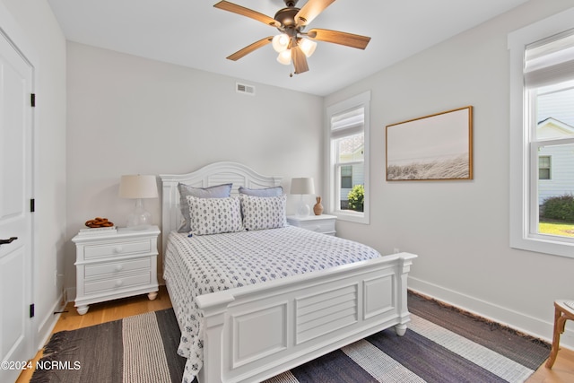 bedroom with ceiling fan, multiple windows, and light hardwood / wood-style flooring