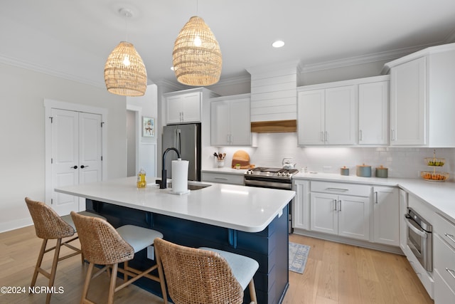 kitchen with stainless steel appliances, white cabinets, an island with sink, and sink