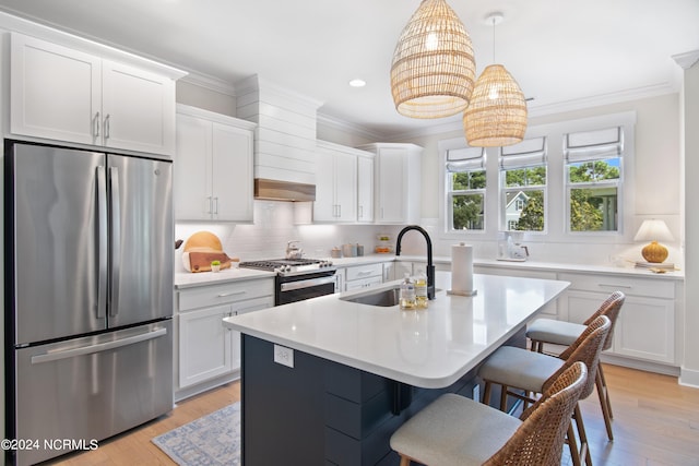 kitchen with white cabinetry, sink, appliances with stainless steel finishes, hanging light fixtures, and light hardwood / wood-style flooring