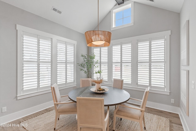 dining area with light wood-type flooring and lofted ceiling