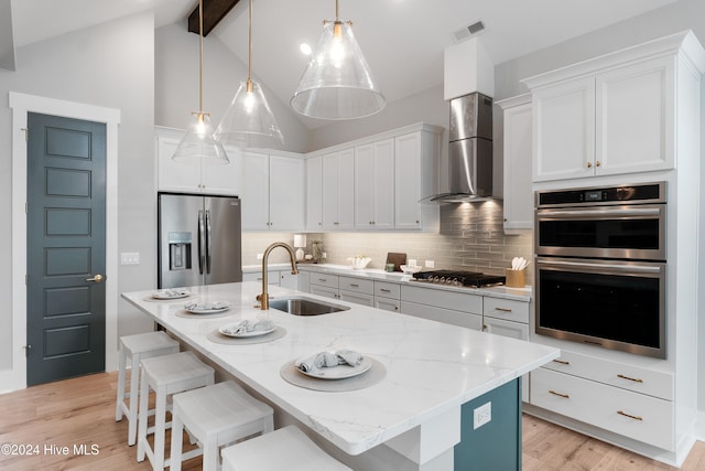 kitchen featuring sink, appliances with stainless steel finishes, wall chimney exhaust hood, light hardwood / wood-style flooring, and white cabinets