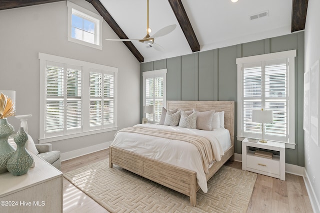 bedroom featuring beam ceiling, multiple windows, ceiling fan, and light hardwood / wood-style flooring