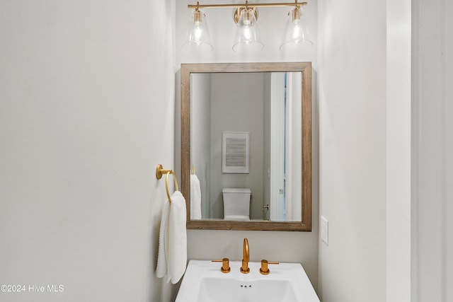 bathroom with toilet, an inviting chandelier, and sink