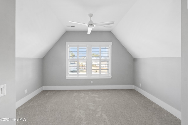 additional living space with vaulted ceiling, light colored carpet, and ceiling fan