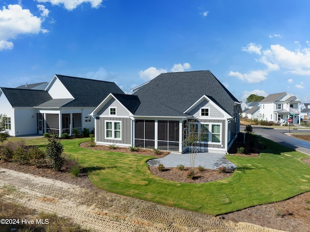 951 Trisail Ter, Wilmington, NC 28412 - rear view of house with a sunroom, board and batten siding, a shingled roof, and a yard
