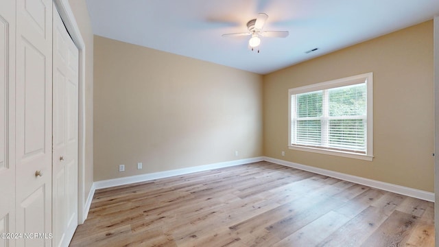 unfurnished bedroom featuring ceiling fan, a closet, and light wood-type flooring