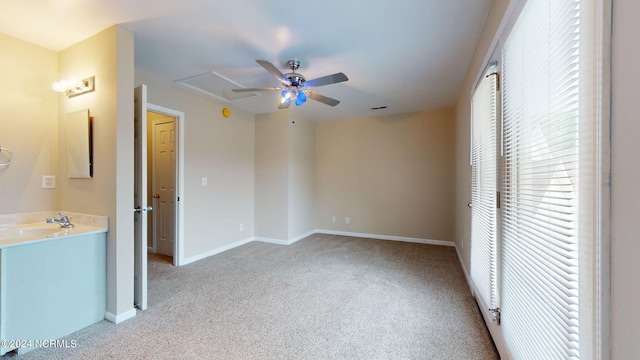 unfurnished bedroom featuring light colored carpet, sink, and ceiling fan