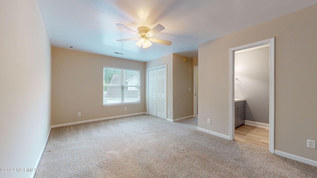 unfurnished bedroom with light carpet, connected bathroom, ceiling fan, and a closet