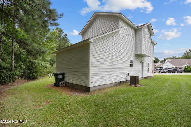 view of side of home with central AC and a yard