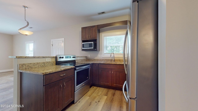 kitchen with appliances with stainless steel finishes, light hardwood / wood-style flooring, light stone countertops, and a wealth of natural light