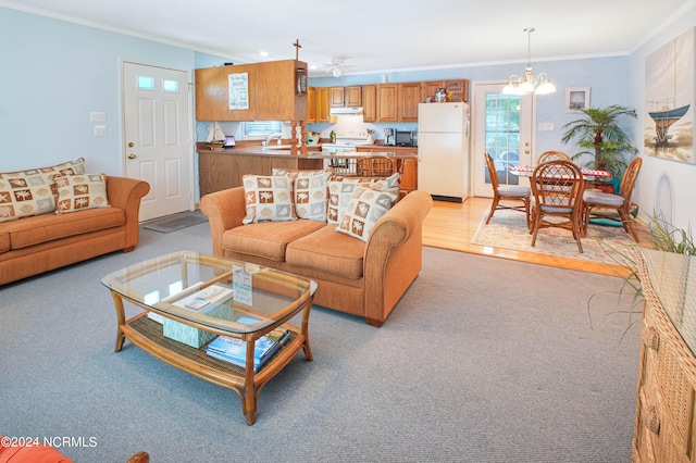 living room featuring ornamental molding, light hardwood / wood-style flooring, ceiling fan with notable chandelier, and sink