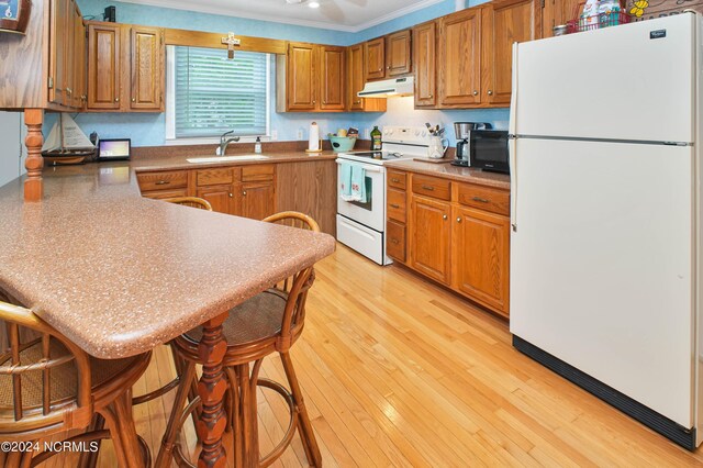 kitchen with light hardwood / wood-style floors, a breakfast bar area, sink, white appliances, and crown molding