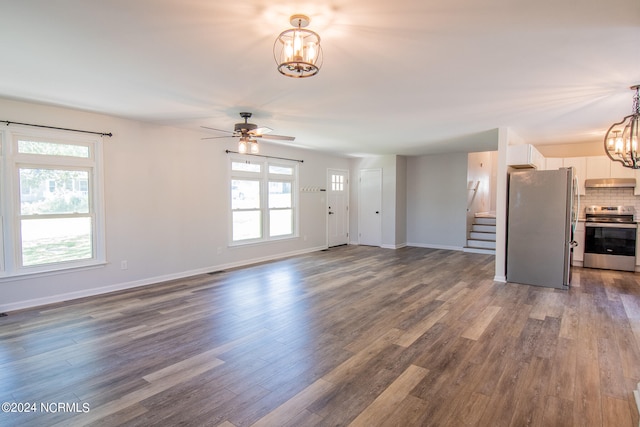 unfurnished living room featuring dark wood-type flooring and ceiling fan with notable chandelier