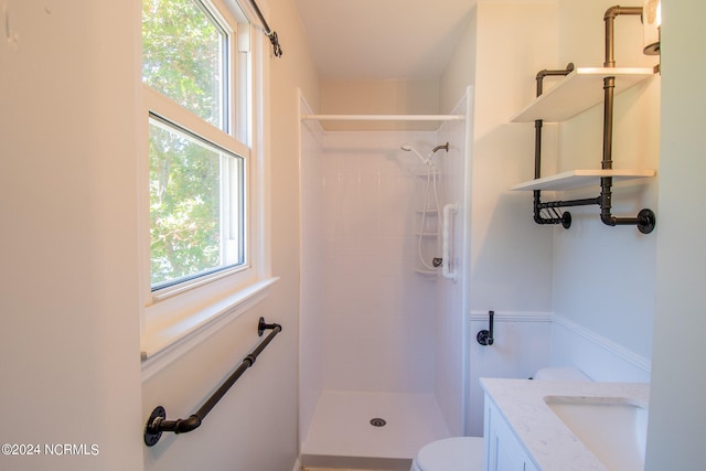 bathroom featuring vanity, toilet, and a tile shower