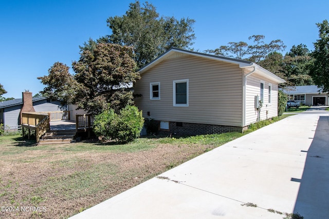 view of side of property featuring a lawn and a deck