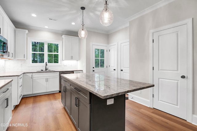 kitchen with white cabinets, a wealth of natural light, light wood-type flooring, and a kitchen island