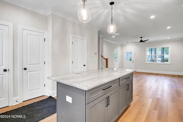 kitchen with gray cabinetry, light wood-type flooring, a center island, decorative light fixtures, and ornamental molding