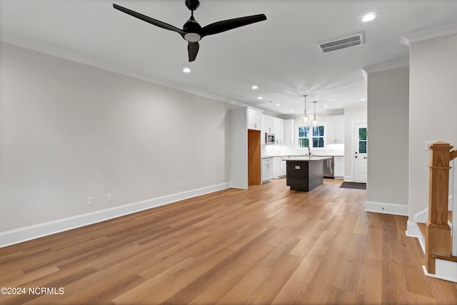 unfurnished living room with light hardwood / wood-style floors, crown molding, sink, and ceiling fan with notable chandelier