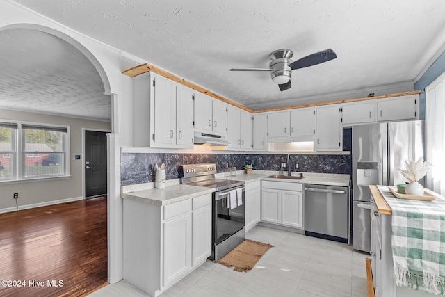 kitchen with stainless steel appliances, sink, a textured ceiling, light hardwood / wood-style flooring, and white cabinets