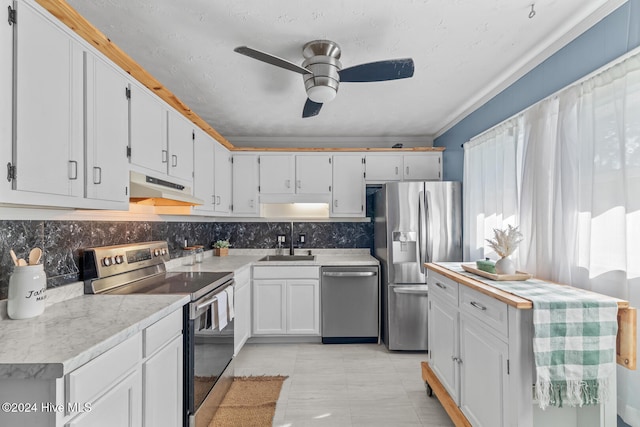 kitchen featuring appliances with stainless steel finishes, decorative backsplash, sink, white cabinets, and ceiling fan