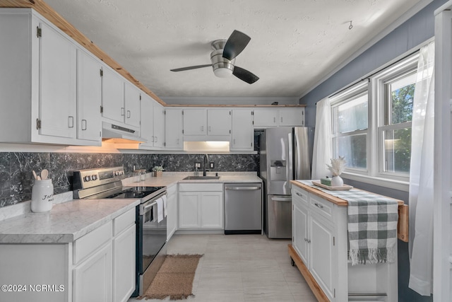 kitchen with tasteful backsplash, appliances with stainless steel finishes, sink, white cabinets, and ceiling fan