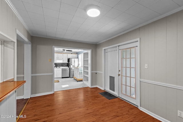 interior space with wooden walls, french doors, light hardwood / wood-style floors, and crown molding