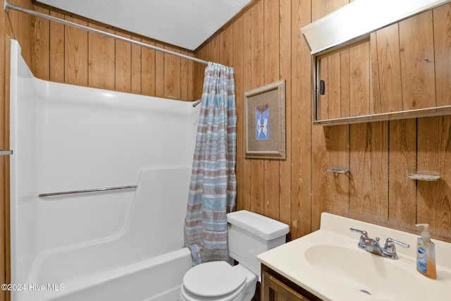 full bathroom with shower / bath combination with curtain, a textured ceiling, toilet, wooden walls, and vanity