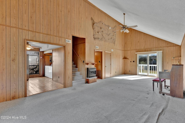 unfurnished living room featuring a wood stove, light carpet, high vaulted ceiling, and ceiling fan