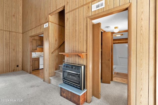 kitchen with light carpet, white range oven, heating unit, and wooden walls