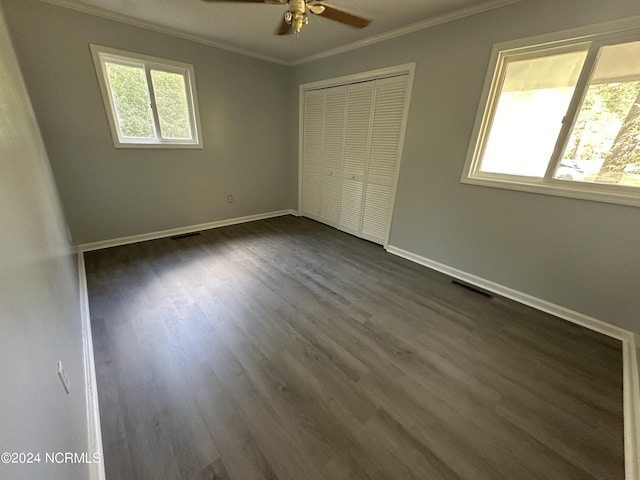 unfurnished bedroom featuring dark wood-type flooring, a closet, ornamental molding, and ceiling fan