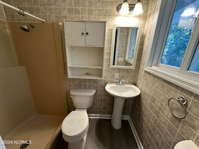 bathroom featuring tile walls, wood-type flooring, tiled shower, and toilet