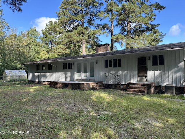 back of property with a yard and central AC