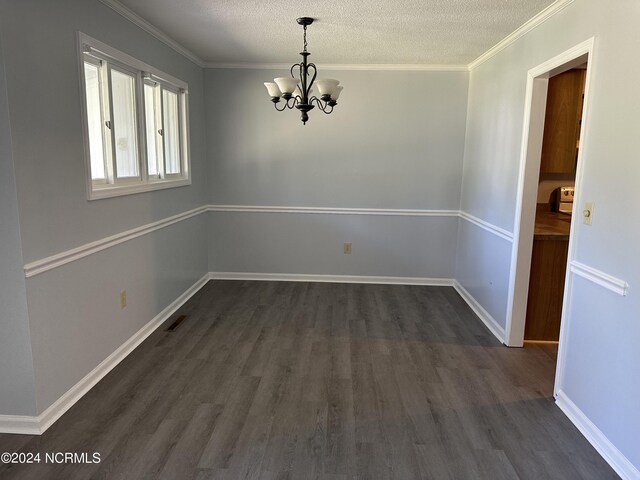 unfurnished dining area featuring a textured ceiling, a notable chandelier, ornamental molding, and dark hardwood / wood-style flooring