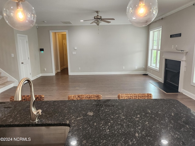 unfurnished living room featuring ceiling fan, dark wood-type flooring, crown molding, and sink