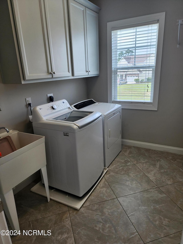 washroom with washer and clothes dryer, cabinets, and dark tile patterned flooring