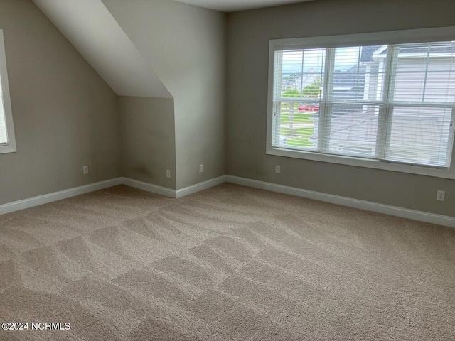 bonus room with vaulted ceiling and light colored carpet