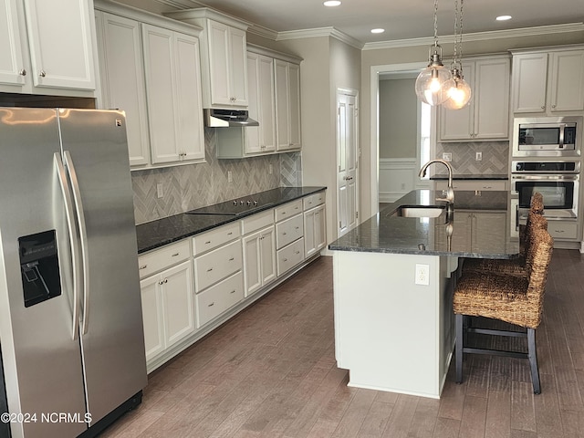 kitchen featuring dark hardwood / wood-style flooring, pendant lighting, stainless steel appliances, a kitchen island with sink, and sink