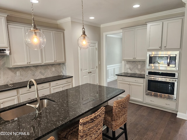 kitchen featuring stainless steel appliances, dark stone countertops, decorative light fixtures, and dark hardwood / wood-style flooring