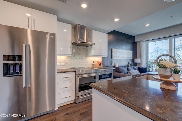 kitchen with white cabinetry, sink, wall chimney exhaust hood, dark hardwood / wood-style flooring, and appliances with stainless steel finishes