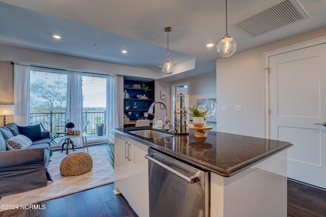 kitchen featuring dishwasher, sink, dark wood-type flooring, hanging light fixtures, and a center island with sink