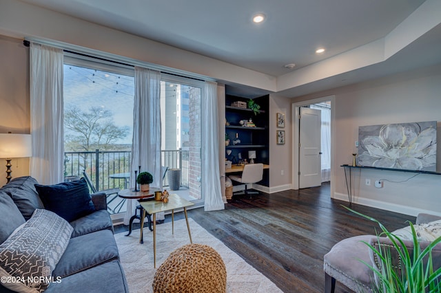 living room with built in shelves and dark hardwood / wood-style floors