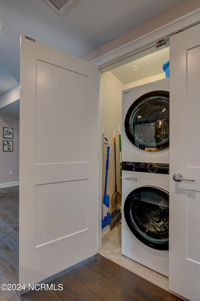 washroom with hardwood / wood-style floors and stacked washer and dryer