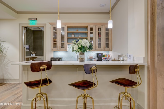 bar featuring decorative light fixtures, light wood-type flooring, ornamental molding, and backsplash