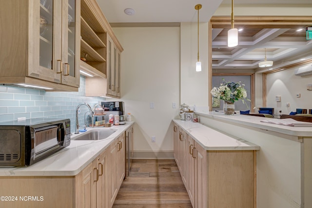 kitchen featuring beam ceiling, sink, coffered ceiling, kitchen peninsula, and decorative light fixtures