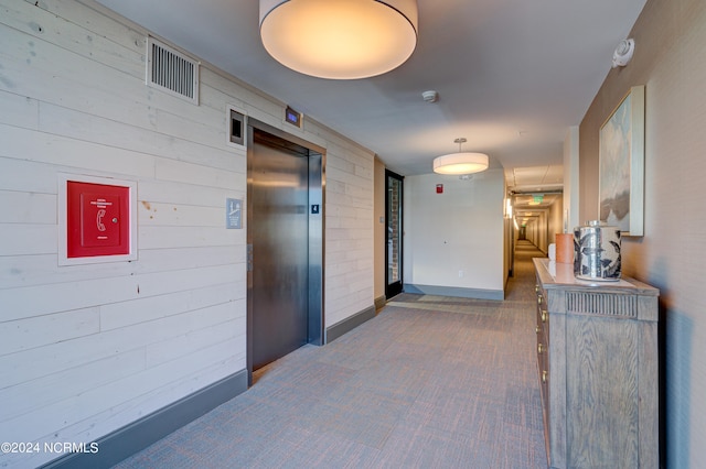 hall featuring elevator and wooden walls