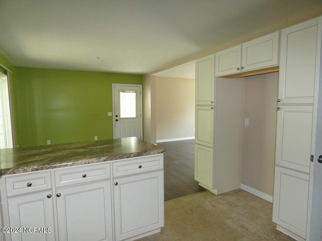 kitchen with light floors, white cabinetry, and baseboards