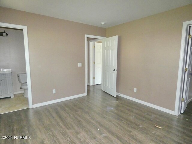 unfurnished bedroom with baseboards, ensuite bath, and wood finished floors