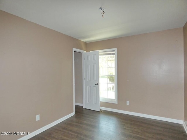 empty room featuring baseboards and dark wood finished floors