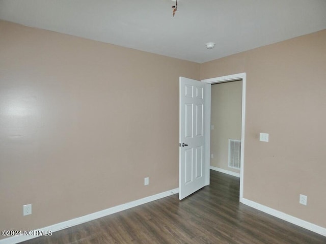 unfurnished room with visible vents, dark wood-type flooring, and baseboards